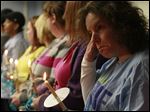  LCCS case worker Denise Greenblatt, right, and other LCCS employees hold candles during the memorial.  