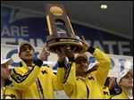  Michigan gymnasts hold up the national team trophy at the end of the NCAA college men's gymnastics championship Saturday in State College, Pa.