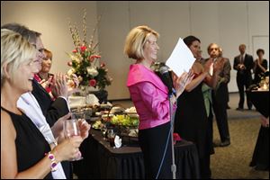 Event co-Chair Cindy Taylor, center, claps as she names off the Pink Tie Guys, men who have helped in the search for a cure for cancer, Saturday evening during the Pink Ribbon Gala at the SeaGate Convention Centre in downtown Toledo.