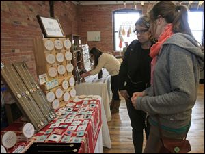 Linda Fiely, left,  of Columbus, and Cleo Brengman, a student at Bowling Green State University, look at the artwork of Amy Cronkite, creator of ‘My Marigold,’ of Detroit. 