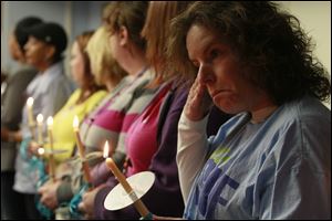 LCCS case worker Denise Greenblatt, right, and other LCCS employees hold candles during the memorial.  