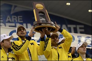 Michigan gymnasts hold up the national team trophy at the end of the NCAA college men's gymnastics championship Saturday in State College, Pa.