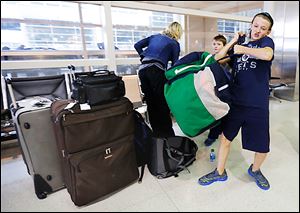 Jackson Sabo, 12, collects gear shortly after he and his family, including brother Ryker, 8, in back, and their mother, Kelly, reached Detroit Metropolitan Airport. The family from Rosemont, Minn., traveled to the Detroit area for a hockey tournament. Its bag of sticks did not arrive. 