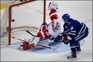 Vancouver Canucks' Maxim Lapierre scores the winning goal past Detroit Red Wings' goalie Jimmy Howard in a shootout Saturday in Vancouver, B.C.