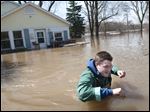  Joe Biggerstaff wades away from his mother's Konkle Drive home on the Grand River north of downtown Grand Rapids, Mich., Sunday.