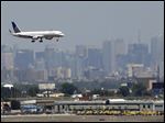  FILE - In this July 10, 2012 file photo, a United plane prepares to land at Newark Liberty International Airport in Newark, N.J., with the New York City skyline in the background. Commercial airline flights moved smoothly throughout most of the country on Sunday, April 21, 2013, the first day air traffic controllers were subject to furloughs resulting from government spending cuts, though some delays appeared in the late evening in and around New York. The real test, however, will come Monday, when traffic ramps up. (AP Photo/Julio Cortez, File)