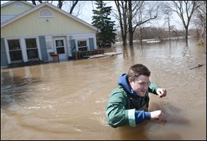 Joe Biggerstaff wades away from his mother's Konkle Drive home on the Grand River north of downtown Grand Rapids, Mich., Sunday.