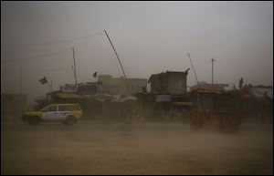 A taxi tries to make its way through a sandstorm that obscures the city of Kanadahar, Afghanistan, Sunday.