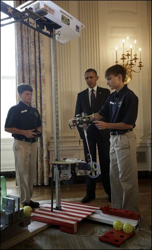 President Barack Obama watches as Thomas Shields, 13, left, and Rush Lyons, 14, right, demonstrate their robot 'Vator', which was designed to mimic a space elevator.