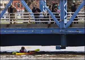 Spectators watch as a kayaker ducks underneath the blue bridge on the Grand River in downtown Grand Rapids, Mich., Sunday.