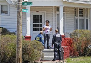 Angela Self talks to Dave Dustin, an FBI special agent, and Officer Melvin Haney of the Toledo Police Gang Unit at her home on Fernwood Avenue during their canvassing of the neighborhood.