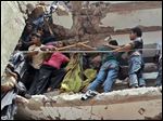  Bangladeshi rescuers squeeze through a gap to help pull out survivors spotted in the debris of a building that collapsed in Savar, near Dhaka, Bangladesh, Wednesday, April 24, 2013. An eight-story building housing several garment factories collapsed near Bangladesh’s capital on Wednesday, killing dozens of people and trapping many more under a jumbled mess of concrete. Rescuers tried to cut through the debris with earthmovers, drilling machines and their bare hands. (AP Photo/A.M.Ahad)