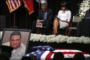 President Obama and first lady Michelle Obama bow their heads behind a photo of volunteer firefighter Capt. Cyrus Adam Reed, who was killed, as they attend the memorial for victims of the fertilizer plant explosion in West, Texas.