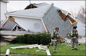 Toledo police and firefighters examine a house at 1448 N. Huron St. that collapsed after a large explosion Thursday.