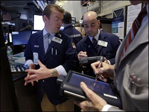 In this Tuesday, April 16, 2013, photo, Specialist Michael O'Mara, left, and trader Fred Demarco work on the floor of the New York Stock Exchange. World stock markets fell today after Japan faced an unwelcome drop in consumer prices. 