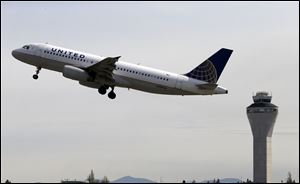 In this April 23, 2013 photo, a United Airlines jet departs in view of the air traffic control tower at Seattle-Tacoma International Airport in Seattle. With flight delays mounting, the Senate approved hurry-up legislation Thursday night to end air traffic controller furloughs.