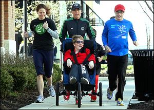 Erin O'Connell, left, Toledo Roadrunners volunteer coordinator, Jessy Meeker, and Mark Armstrong push Robin Hanna Mower on the first leg of the 3-mile run during the weekly Second Sole of Toledo run at Levis Commons in Perrysburg. Mrs. Mower will participate in Sunday’s race.