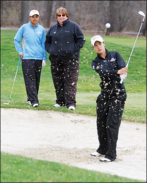UT golfer Sathika Ruenreong, left, and coach Nicole Hollingsworth watch Manisa Isavas practice recently at the Toledo Country Club. Ruenreong fired a 77 and Isavas a 78 at Friday's MAC tournament.