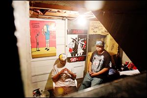 Aaron Belton, left, and his brother Christopher Belton sit in their basement recording studio where Christopher composes music for his group Flip Cash. 