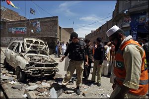 Pakistani police officers and volunteers visit the site of an explosion in Peshawar, Pakistan.