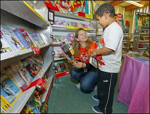 PTA President Kate Schmus helps kindergartner Ireese Vinson, 6, choose books at Temperance Road Elementary’s book fair. The building is to close at the end of  this school year. 