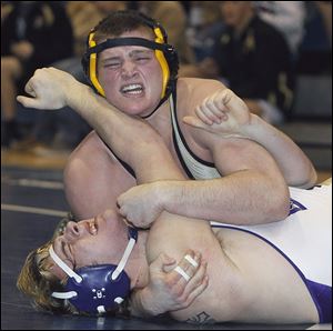 Perrysburg’s Mark Delas holds down Maumee’s Nick Grzegorzeski while winning the 220-pound final at the Northern Lakes League wrestling championships.