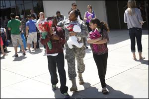 Sgt. Renata Morgan, of North Toledo, center, talks with her son Kelvin Gist, Jr., 11, left, and niece Ja'Lycia Price, 9, right, Thursday afternoon at the conclusion of the welcome home ceremony held for the 323rd Military Police Company at Cedar Creek Church in Perrysburg.