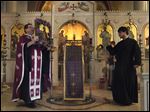  Fr. Aristotle Damaskos walks with an icon during Tuesday's Holy Week service at Holy Trinity Greek Orthodox Cathedral in Toledo, Ohio.  At right is seminarian David Mynihan.