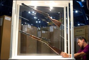 Johnny Bass sets up the Henry Repeating Arms Company booth as exhibitors prepares for National Rifle Association convention.