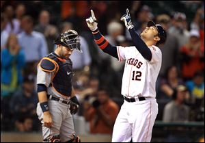 Houston Astros' Carlos Pena (12) celebrates as he walks past Detroit Tigers catcher Alex Avila after hitting a home run during the fourth inning.
