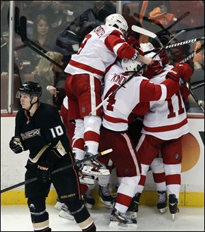 Detroit Red Wings players celebrate Gustav Nyquist's goal during overtime as Anaheim Ducks' Corey Perry (10) skates off in Game 2 of their first-round NHL hockey Stanley Cup playoff series.