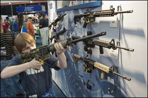 A young man who chose not to give his name sizes-up an assault style rifle during the National Rifle Association's annual convention.