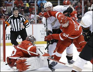 Wings defenseman Niklas Kronwall clears the puck from Anaheim's Corey Perry in front of Red Wings goalie Jimmy Howard during the first period.