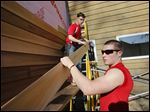   Jonathan Wiemer, 17, of Ottawa Hills, left, and Corey Donnelly, 17, of Northview install siding on the Olander Park administration building in Sylvania on Wednesday.
