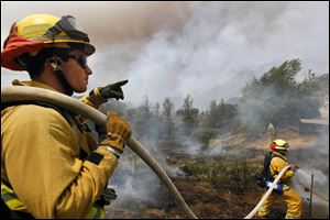 Firefighters from Riverside, Calif. work to extinguish a brush fire at Point Mugu, Calif.,  Friday.