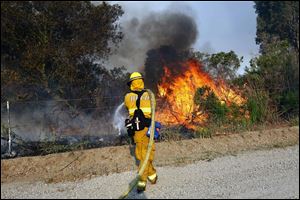 A firefighter from Huntington beach works to extinguish a brush at Point Mugu Friday.