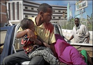 A Somali man carries a wounded child in the back of a pickup truck to a hospital, following a suicide car bomb blast in the capital Mogadishu, Somalia today.