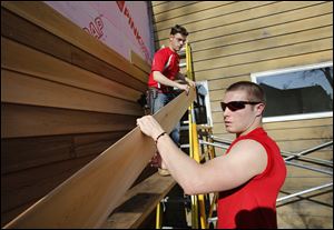  Jonathan Wiemer, 17, of Ottawa Hills, left, and Corey Donnelly, 17, of Northview install siding on the Olander Park administration building in Sylvania on Wednesday.
