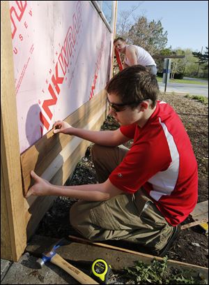Ryan Kiker, 17, front, and Skylar Gilbert, 17, both students at Northview High School, fit a piece of siding on the  administration building at Olander Park. Students spend five weeks making repairs.
