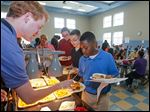   Ryan McIntosh serves chicken nuggets to Ka’ron Turner, right, Logan Jeziorowski, behind Ka’ron, and Charlette Hornyak, all seventh graders at Larchmont Elementary School. The school is testing six menu items to see if they make the grade at the school. Nine other schools are helping evaluate meals.