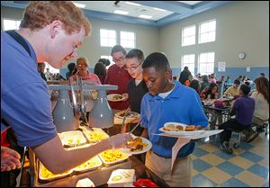  Ryan McIntosh serves chicken nuggets to Ka’ron Turner, right, Logan Jeziorowski, behind Ka’ron, and Charlette Hornyak, all seventh graders at Larchmont Elementary School. The school is testing six menu items to see if they make the grade at the school. Nine other schools are helping evaluate meals.