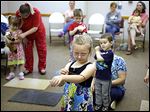  Eliana Kilyard, 5, pulls a pretend worm across her arm as she lis-tens to a  reading of ‘Worms for Lunch’ at the Delta Public Library. Voters on Tuesday approved a 2-mill levy to support the library.  