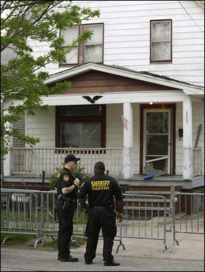 Sheriff deputies stand outside a house in Cleveland where Amanda Berry, Gina DeJesus, and Michelle Knight were found more than 10 years after they vanished.