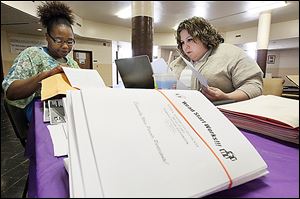 Ashley Fowlkes, left, gives paperwork to Michelle Rodriguez as she registers her daughter for the Head Start program. Enrollment continued Tuesday at the J.B. Simmons Community Center.