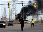  A  Melvindale police officer in a haz-mat mask directs traffic as a fire burns at the Marathon refinery in Detroit after an explosion April 27. 
