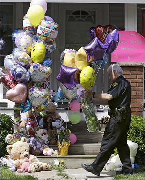 A Cleveland policeman carries balloons and flowers to the front porch of a home awaiting the arrival of Amanda Berry on Wednesday. 