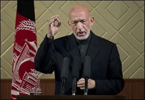Afghan President Hamid Karzai gestures during a ceremony at Kabul University in Kabul, Afghanistan, today. Karzai said he is ready to let the U.S. have nine bases in the country after the 2014 combat troop pullout, but wants Washington’s “security and economic guarantees” first.