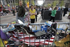 People pause to look at a makeshift memorial today near the Boston Marathon finish line.