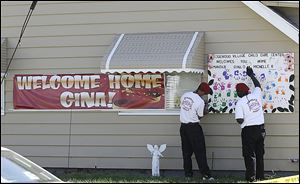 Guardian Angels hang a poster at the home of Gina DeJesus, one of three women freed on Monday.