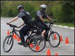  Defiance patrolmen Tim Monhollen, left, and Rashuan Amey navigate around cones during a police mountain bike training course at Memorial Park in Sylvania.